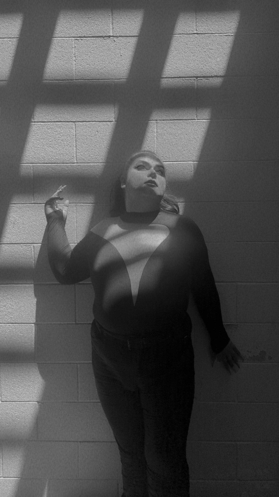 A plus-size trans person with light skin in a red top, brown halter top, and black clothing.