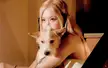 Rosé with blonde hair holding a small white dog in a close-up