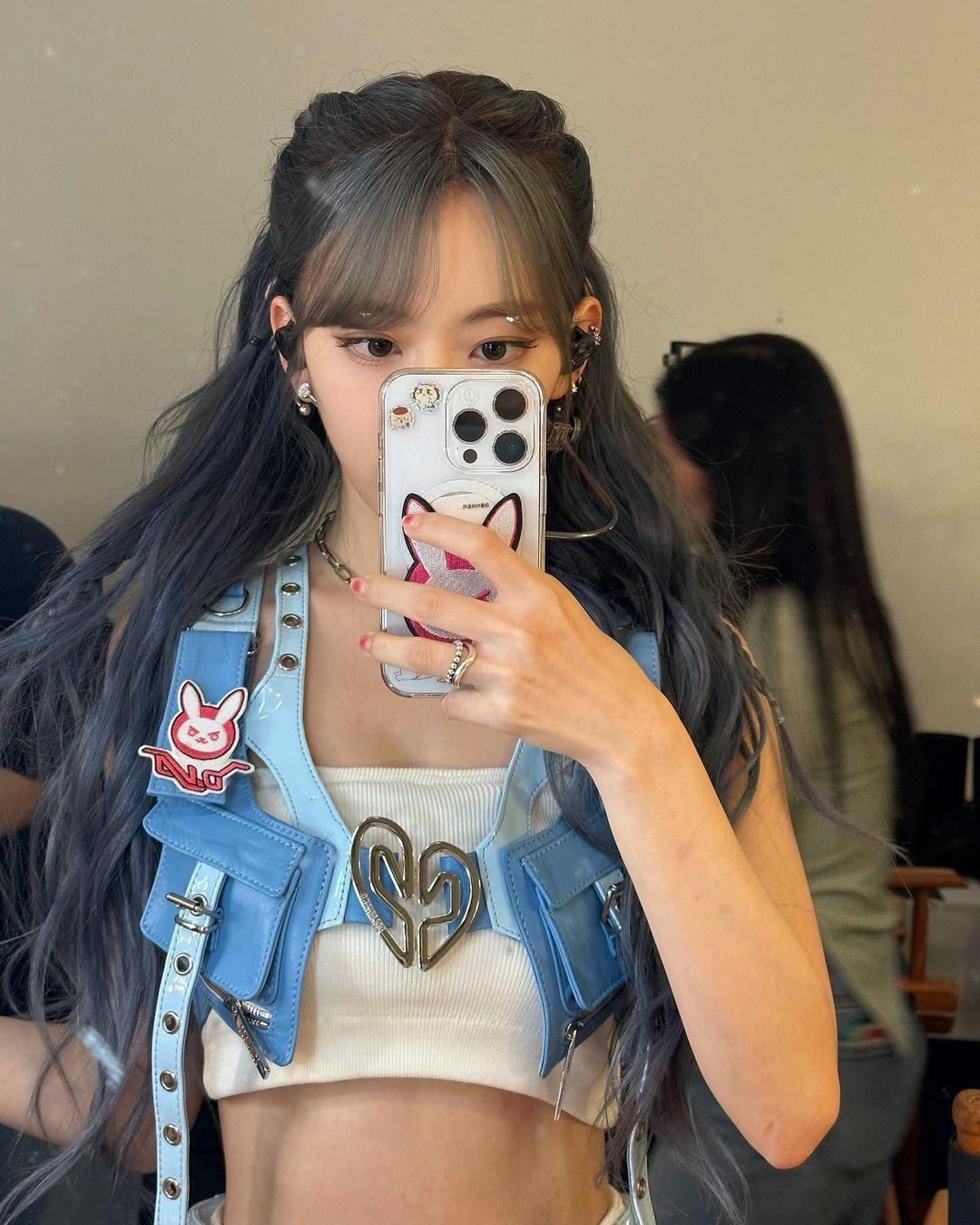 Sakura in a blue denim vest, white crop top, and short skirt with greyish-blue hair