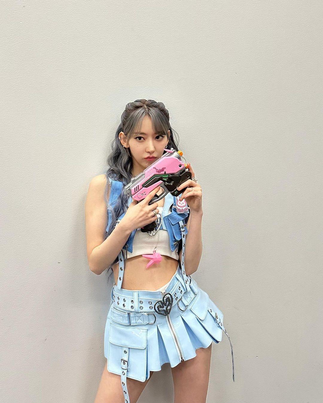 Sakura in a blue denim vest, white crop top, and short skirt with greyish-blue hair