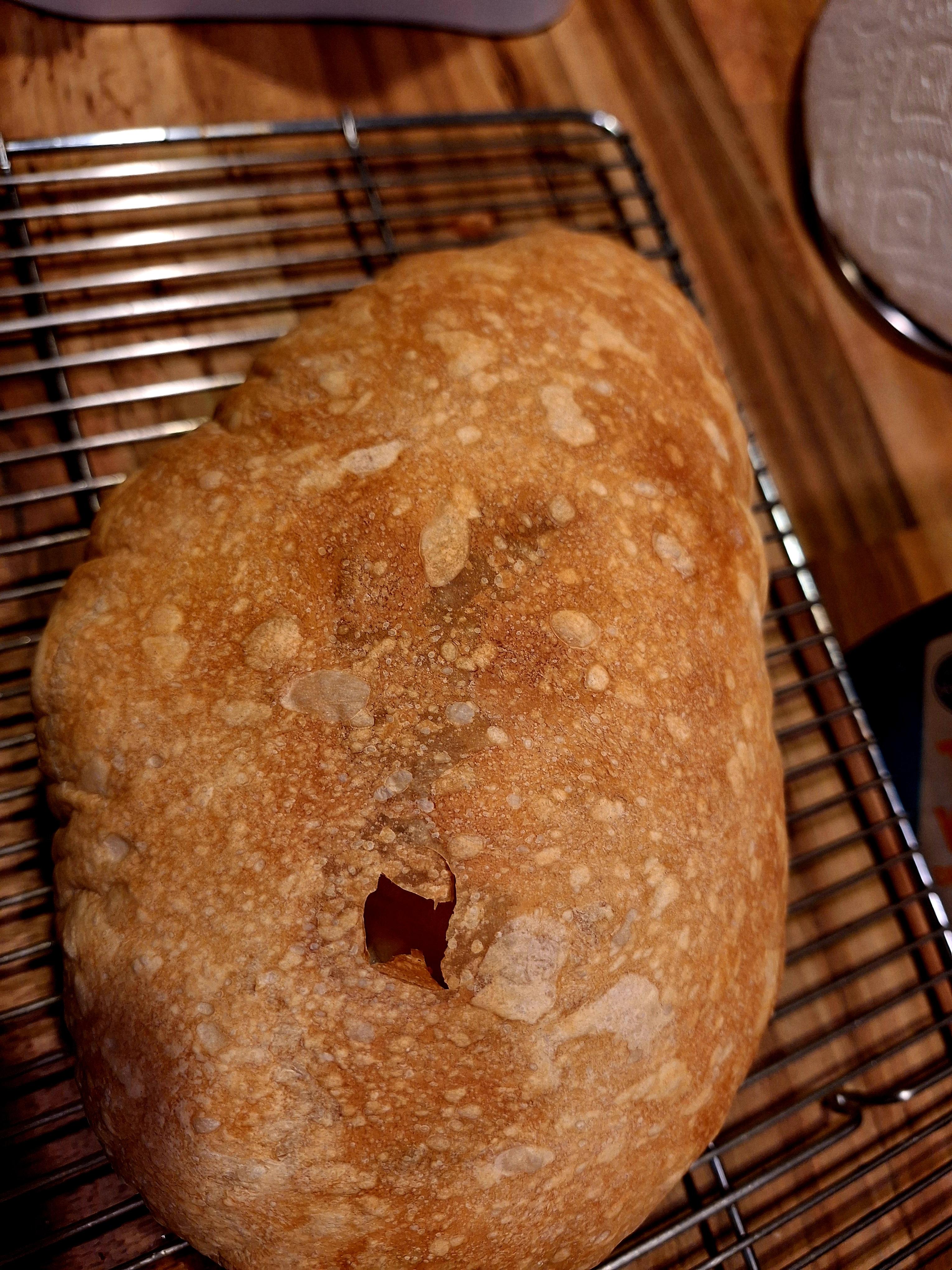 Oddly inflated ciabatta-esque bread baking in an oven and sliced on a cooling rack