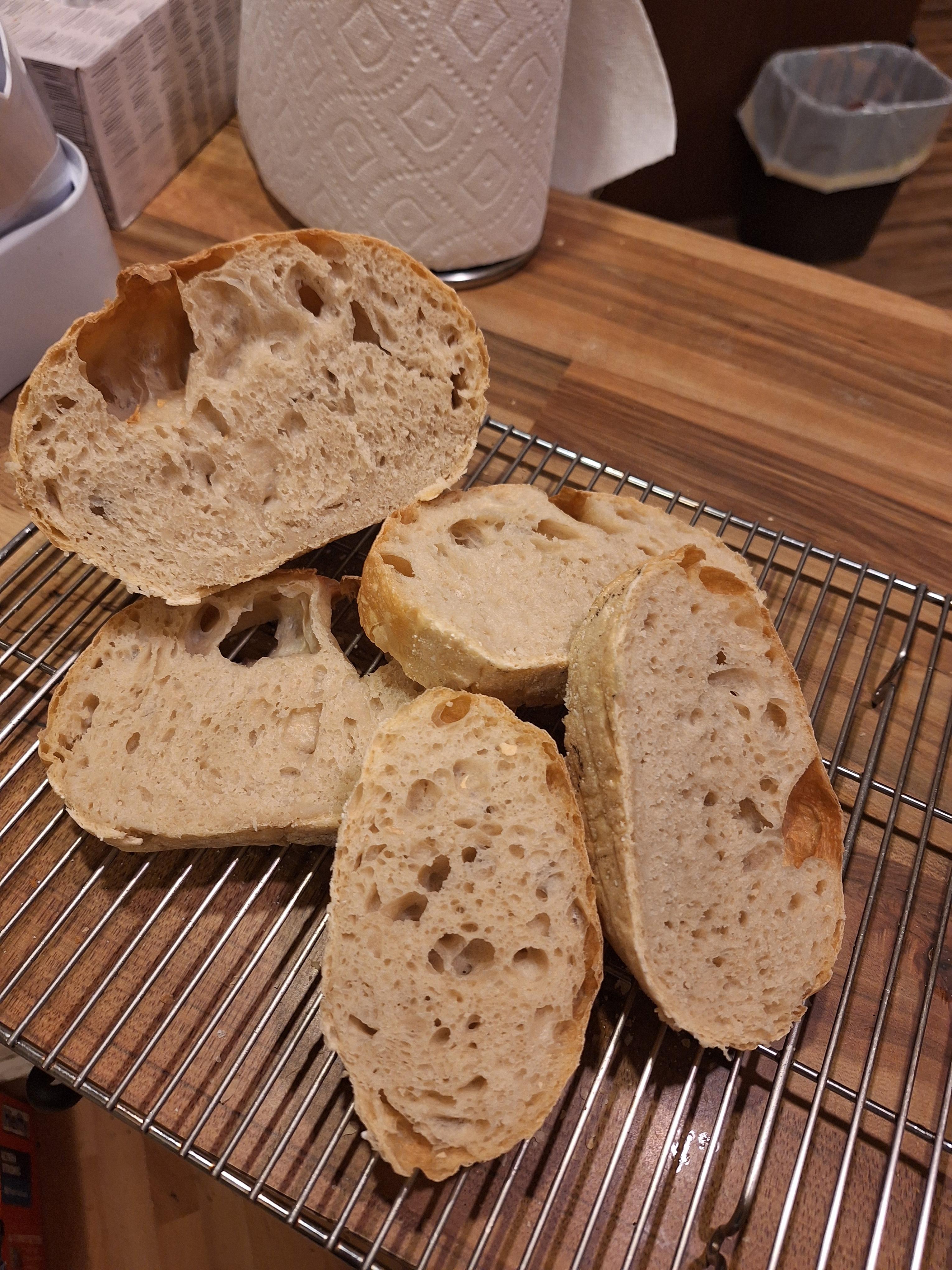Oddly inflated ciabatta-esque bread baking in an oven and sliced on a cooling rack