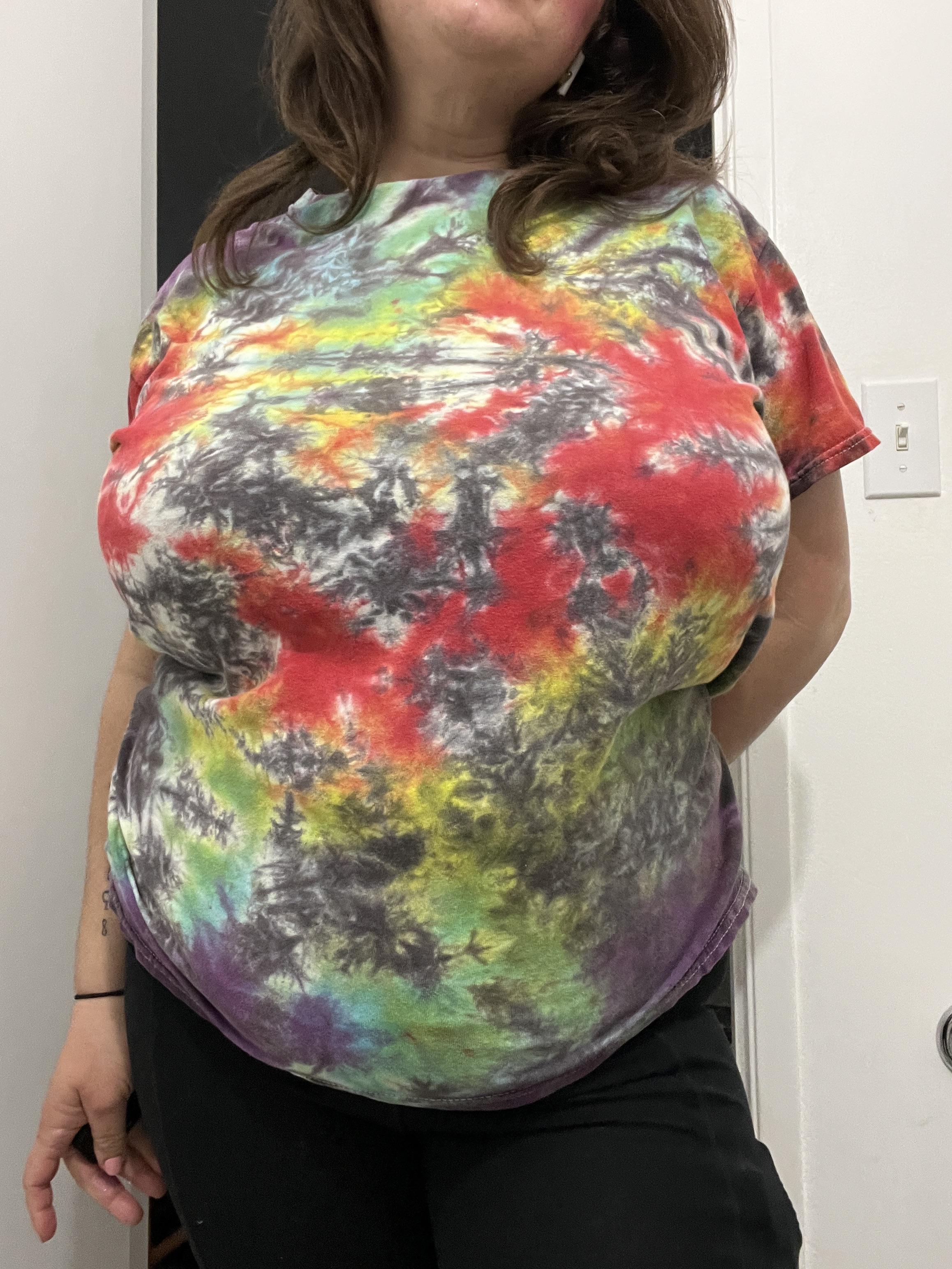 Busty white BBW woman in a colorful tie-dye t-shirt and tight black leggings posing for a selfie.
