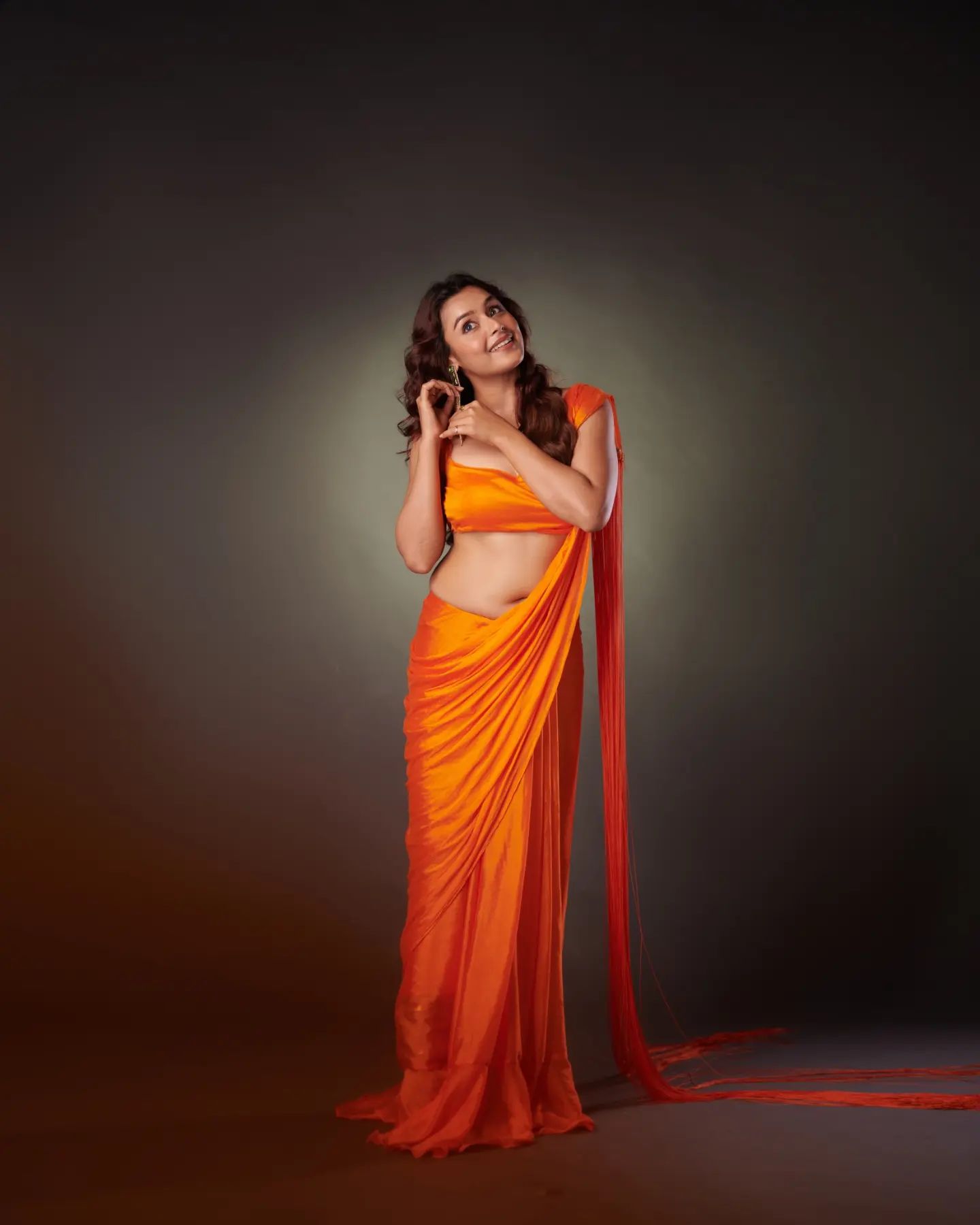 Mokksha Sengupta, a curvy Indian woman wearing an orange sleeveless blouse and matching saree.