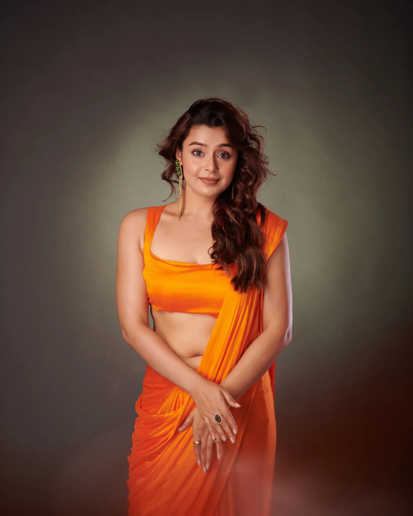 Mokksha Sengupta, a curvy Indian woman wearing an orange sleeveless blouse and matching saree.