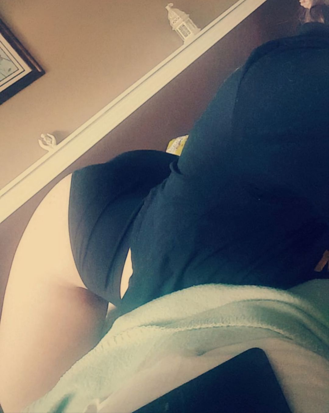 Sissy in a short black skirt bending over to show their curvy backside and thick thighs in a bedroom selfie.