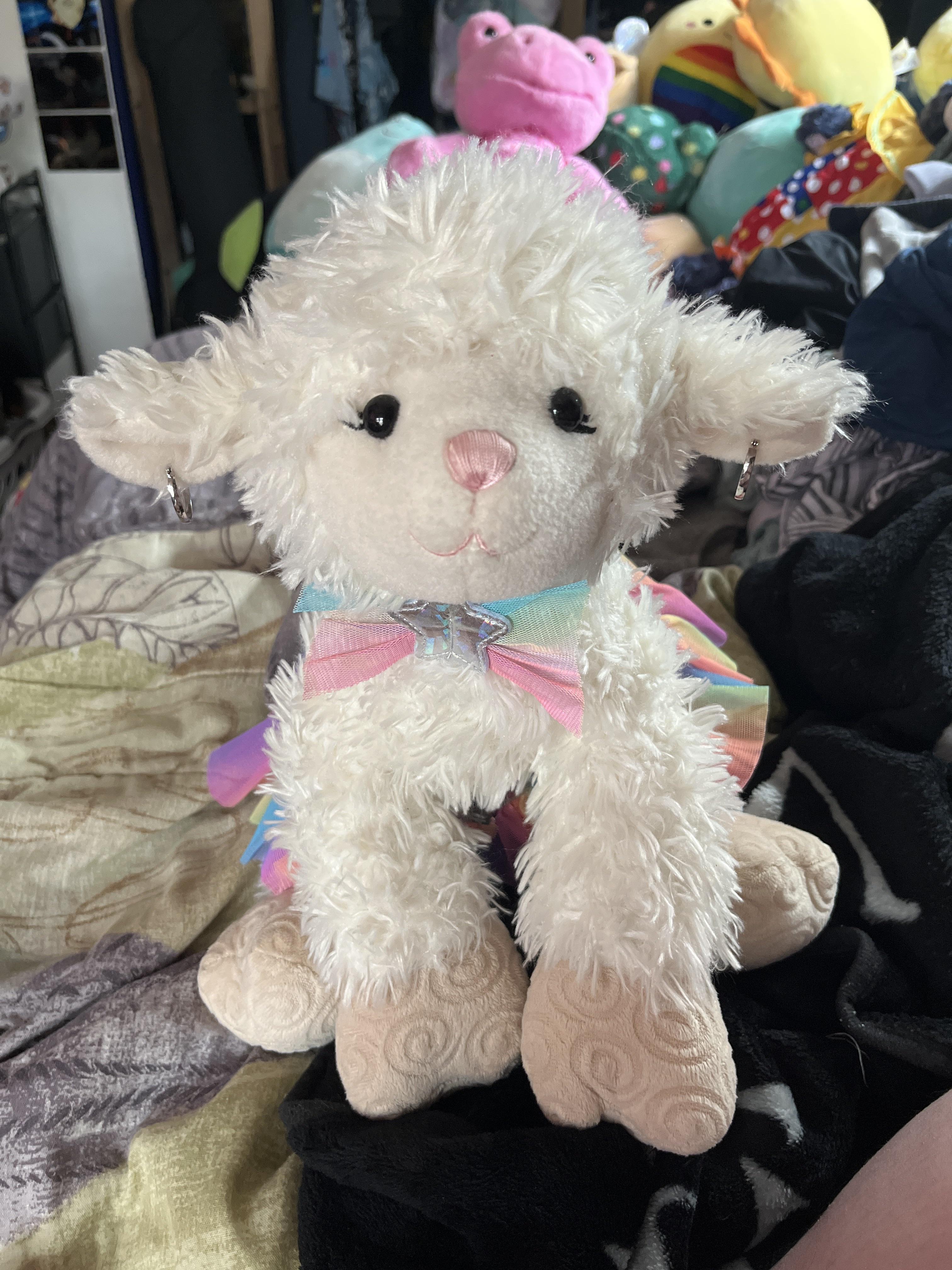 Eleanor the Build-A-Bear stuffed lamb wearing a rainbow tutu, rainbow bow, and hoop earrings