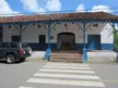 Museo de la Nacionalidad building with a blue porch, tiled roof, and a dark SUV parked by a crosswalk