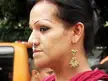 Close-up profile of a beautiful Indian woman with dark hair, wearing a nose ring and ornate gold earrings.
