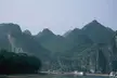Boats cruising the Li River surrounded by steep green karst mountains and trees.