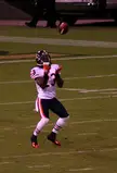 Football player in white jersey number 23 and blue pants catching a football on a grass field