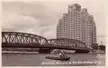 Broadway Mansions and Garden Bridge in 1930s Shanghai with a couple in light-colored clothing