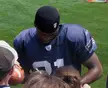 Antwain Spann in a blue football jersey and black skull cap looking down on a grassy field