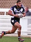 Fabian Goodall in a black and white rugby kit running with a rugby ball on a grass field