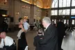 Vintage wedding photos of a group in formal attire, including a strapless black dress, in a brick hall with arched windows