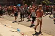 A group of people wearing adult diapers, costumes, and revealing clothing walking down a city street.