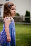 Madeline wearing a blue floral print sundress and a colorful necklace in a grassy yard