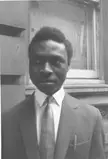 Bankole, a 20th-century Nigerian male musician, in a black and white close-up wearing a dark suit and patterned tie.