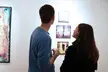 A man and woman from a back view looking at abstract art oil paintings in a gallery.