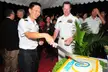 Chew in a white naval uniform cutting a cake with a sword alongside Cmdr. Chuck Good and other guests.