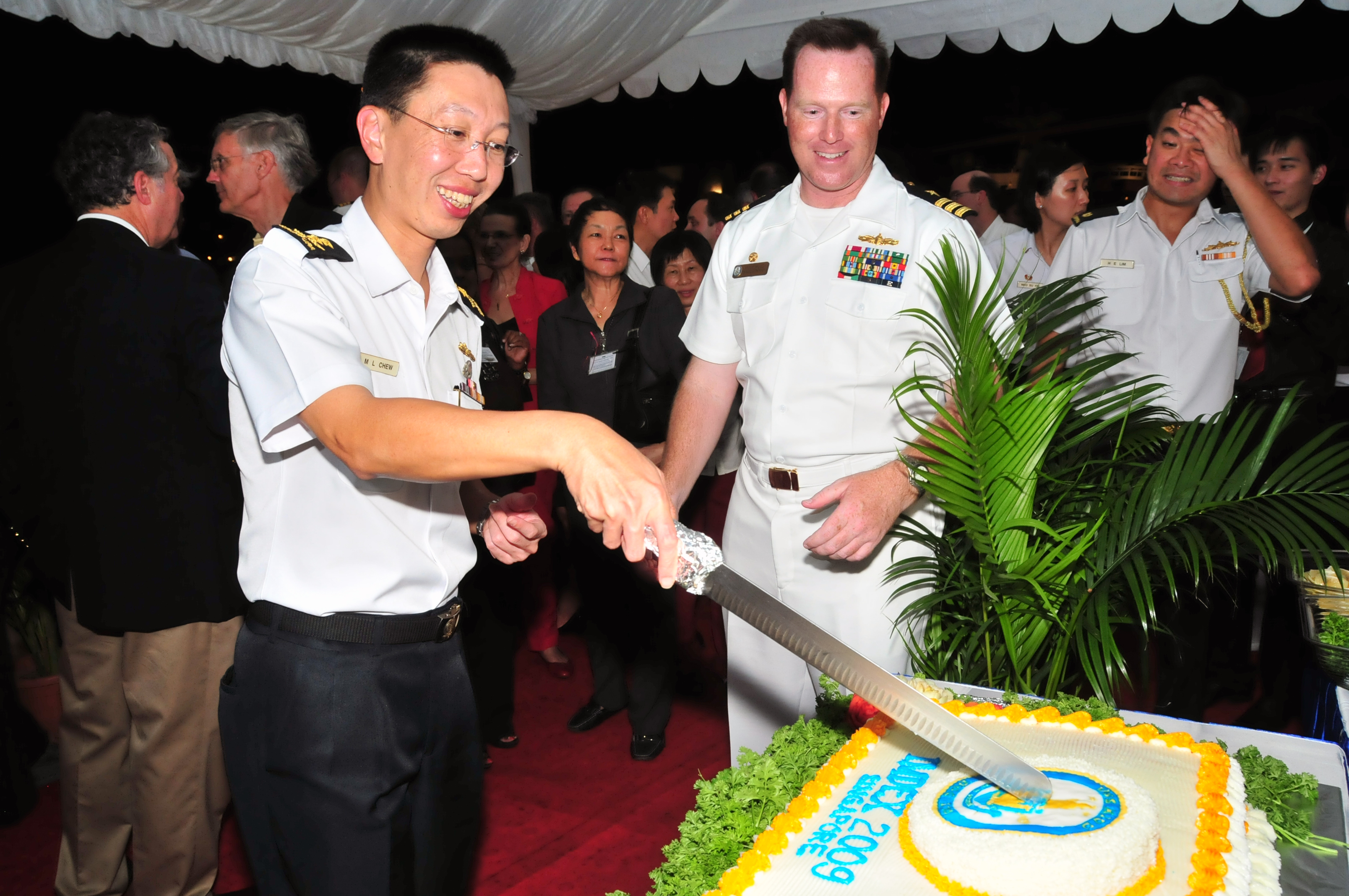 Chew (holding knife) at a cake cutting ceremony in Singapore on 13 May 2009 with Cmdr. Chuck Good of the US Navy.