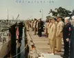 Coast Guard Squadron One personnel in tan and blue uniforms standing in formation on a wooden pier by a boat