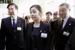 Queen YUNA KIM and a group of people in dark business suits and blazers with fair skin and dark hair.