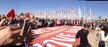 Greenpeace group at the United Nations entrance with red banners and international flags under a blue sky