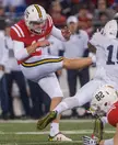 Brad Craddock in a red and white football uniform kicking an opponent on a football field