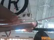 Close-up side view of a silver vintage aircraft tail with a black CA logo inside a hangar