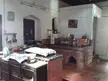 Rustic kitchen with a built-in brick oven, red tiled floors, and white walls