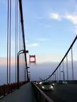 Golden Gate Bridge in San Francisco with cars on a pedestrian walkway and a tower emerging from the fog