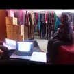 Atika Beauty wearing a purple hijab and skinny blue jeans sitting in a clothing store with a laptop and sneaker boxes