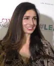 Stern smiling in a leopard print patterned dress with red lipstick and long brown hair