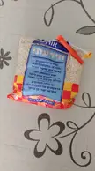 A clear plastic bag of Ben-Gurion's Rice (Israeli couscous) with a blue and red label on a grey surface.