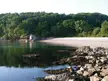 Ruined private bathing house at Elberry Cove with a rocky shoreline, sandy beach, and dense forest.