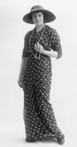 Nesbitt in 1913 wearing a floral print dress, wide-brimmed hat, and long pearl necklace in black and white