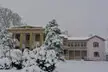 Snowfall at the Belle Meade Plantation in Tennessee with a historic building and snow-covered trees and bushes
