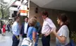 Martín Lousteau with neighbours on a city sidewalk, including a woman in a red dress and people in blue jeans.