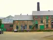 Holehouse abandoned brick industrial building with green doors, a tall chimney, and BMW cars