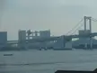 Rainbow Bridge suspension bridge crossing water with a city skyline and spherical structure in the background
