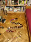 Crochet animals and small dolls arranged in a curved line on a wooden parquet floor in a living room.