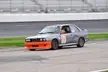 BMW race car with orange accents and number 52 on a track with stadium seating