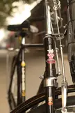 Close-up of a black vintage bicycle frame and fork with chrome accents and Olympic stickers