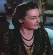 Woman with dark hair and red lipstick in a black beaded v-neck dress from Blood and Sand (1941)