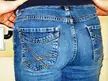 Back view close-up of a person with light skin wearing tight blue denim jeans and a black top.