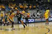 Women's basketball players in green and yellow athletic wear and headbands on a court with spectators