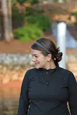 Beautiful woman with brown hair in a bun, wearing a grey headband and black zip-up jacket outdoors.