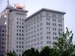 Colcord Building in Oklahoma City, a tall white multi-story building with a red neon sign and green trees.