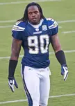 Applewhite, a muscular defensive end with long dark dreadlocks and tattoo sleeves, in a blue and white Chargers uniform.